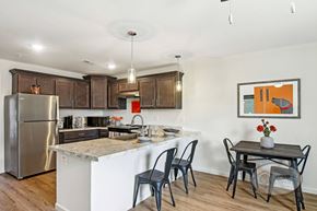 Boiling Springs townhouse for rent - A kitchen with quartz counters, dark cabinets, stainless steel appliances, and a table and chairs.