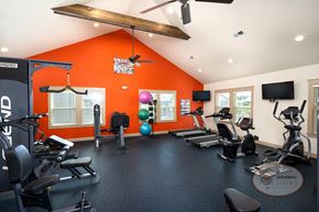 Kodak townhouse for rent - A gym with orange walls and a variety of exercise equipment with flat screen TVs.