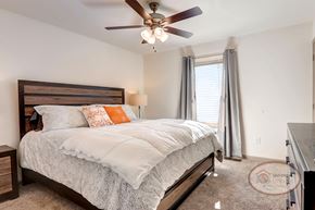 Hendersonville townhouse for rent - A bedroom with a queen size bed, a ceiling fan, carpet, and white walls.