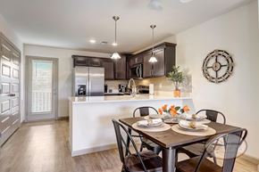 Hendersonville townhouse for rent - A kitchen with a dining area in front, hardwood vinyl floors, white counter tops, dark cabinets, a door to the patio, and stainless steel appliances.