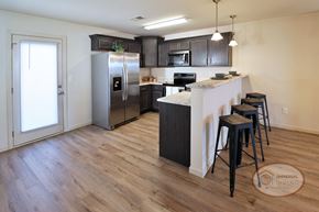 Johnson City townhouse for rent - A kitchen with a refrigerator, stove, and bar stools.