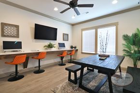 Johnson City townhouse for rent - A business center with orange barstool seating, computers and free Wi-Fi, flat screen TV, large window, and table.