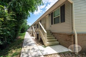 Gray townhouse for rent - The front of a row of tan apartment buildings with a sidewalk leading to stairs.