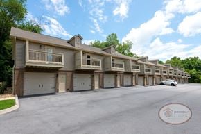 Gray townhouse for rent - A tan row of apartments with balconies and drive-under garages.
