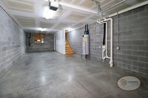 Gray townhouse for rent - A large interior image of a garage with stairs leading to the apartment home above.