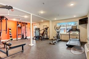 Johnson City apartment for rent - A fitness center with cardio and weight lifting equipment in front of an orange wall.