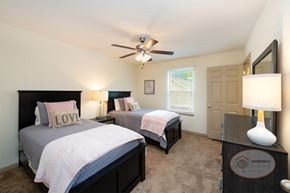 Powell townhouse for rent - A bedroom with two twin beds, carpet, and a ceiling fan.