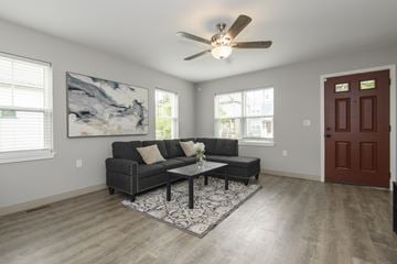 Milwaukee triplex for rent - A living room with a grey couch and a ceiling fan.