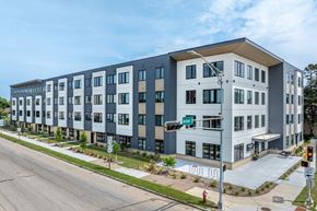 La Crosse apartment for rent - A street view of a modern apartment building with a green street sign.