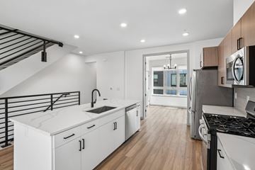 Denver townhouse for rent - A modern kitchen with white cabinets and a black stove top oven.
