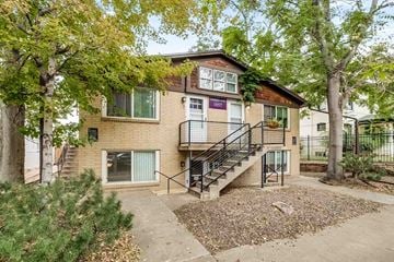 Denver apartment for rent - Apartment number 1057 is surrounded by trees and has a staircase leading to the entrance.
