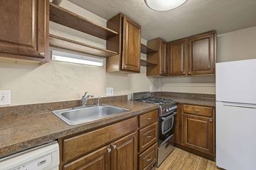 Denver apartment for rent - A kitchen with brown cabinets and a white refrigerator.