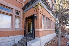 Denver apartment for rent - A red brick building with a black door and steps leading up to it.
