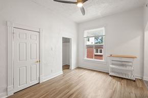 Denver apartment for rent - A room with a white door, a window with a view of a brick building, and a wooden bench.