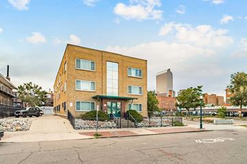 Denver apartment for rent - A brown building with a green awning is in front of a tall building.