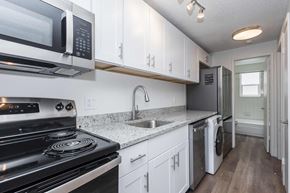 Denver apartment for rent - A kitchen with white cabinets and a black stove top oven.