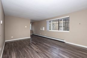 Denver apartment for rent - A room with wooden flooring and a window with bars on it.