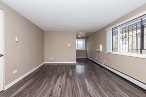 Denver apartment for rent - A room with wooden flooring and a window with bars on it.