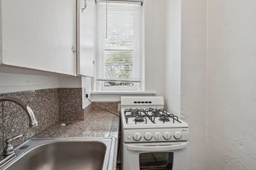 Denver apartment for rent - A white gas stove in a kitchen with a window in the background.