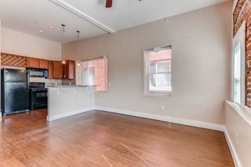 Denver apartment for rent - A kitchen with wooden floors and a black refrigerator.