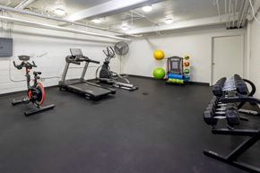 Denver apartment for rent - A gym with a row of treadmills, a stationary bike, and a bench with weights on it.