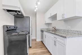 Denver apartment for rent - a kitchen with white cabinets and a stainless steel stove and refrigerator