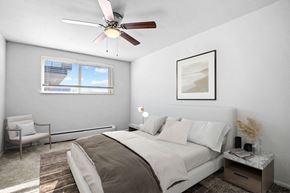 Denver apartment for rent - A bedroom with a bed, chair, and a ceiling fan.