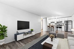 Denver apartment for rent - A modern living room with a television and a kitchen in the background.