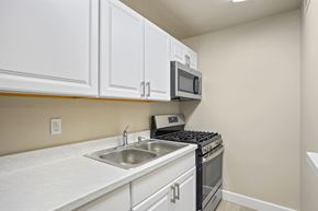 Denver apartment for rent - A kitchen with white cabinets and a stove top oven.