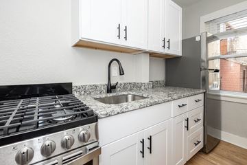 Denver apartment for rent - A kitchen with a black stove top oven and white cabinets.