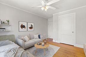 Denver apartment for rent - A living room with a grey couch, a wooden table, and a ceiling fan.
