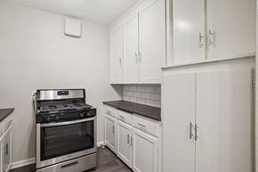 Denver apartment for rent - A kitchen with white cabinets and a stove top oven.