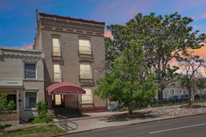 Denver apartment for rent - A building with a red awning is in the foreground of the image.
