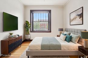 Denver apartment for rent - A bedroom with a large bed and a window overlooking a red building.