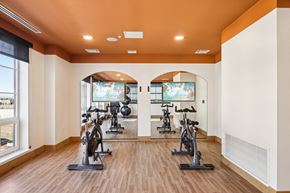 Denver apartment for rent - A spacious room with a row of exercise bikes and a television.