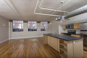 Denver apartment for rent - A kitchen with wooden floors and a black countertop.