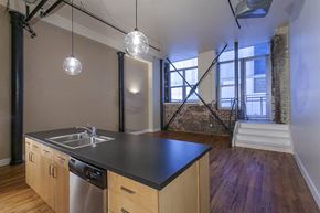 Denver apartment for rent - A kitchen with wooden floors and a brick wall in the background.