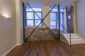 Denver apartment for rent - A room with a wooden floor and a staircase leading to a window.