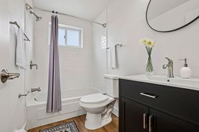 Denver apartment for rent - A white toilet sits next to a bathtub in a bathroom.