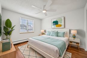 Denver apartment for rent - A bedroom with a bed, a ceiling fan, and a painting on the wall.