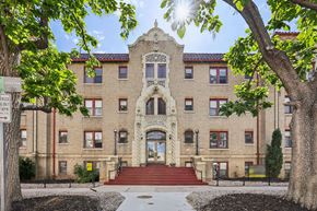 Denver apartment for rent - A large, historic-looking building with a red staircase leading to the entrance.