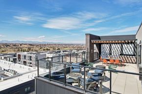 Denver apartment for rent - A modern building with a glass balcony overlooking a cityscape.