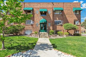 Denver apartment for rent - A brick building with a green awning and a stone pathway leading to the front door.