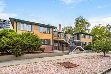 Denver apartment for rent - A building with a green roof and a brick chimney is surrounded by trees and bushes.