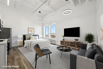 Denver apartment for rent - A modern living room with a grey couch and a bed with white bedding.