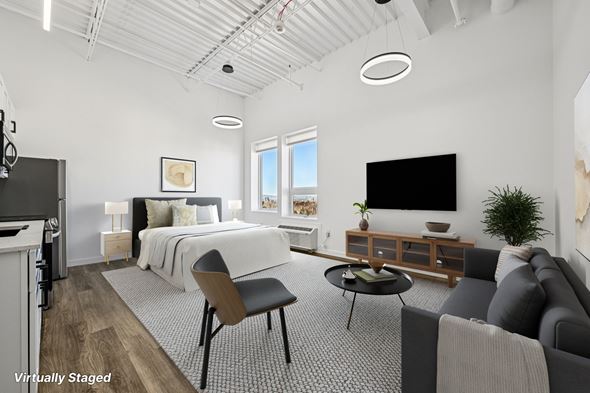 Denver apartment for rent - A modern living room with a grey couch and a bed with white bedding.