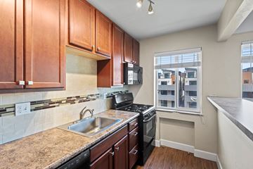 Denver apartment for rent - A kitchen with brown cabinets and a black stove top oven.