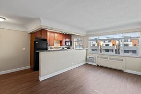 Denver apartment for rent - A spacious living room with a kitchen area and a view of the city.