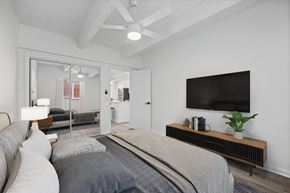 Denver apartment for rent - A modern bedroom with a large bed and a flat screen TV on the wall.