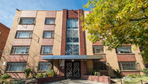 Denver apartment for rent - A red brick building with a black gate in front.